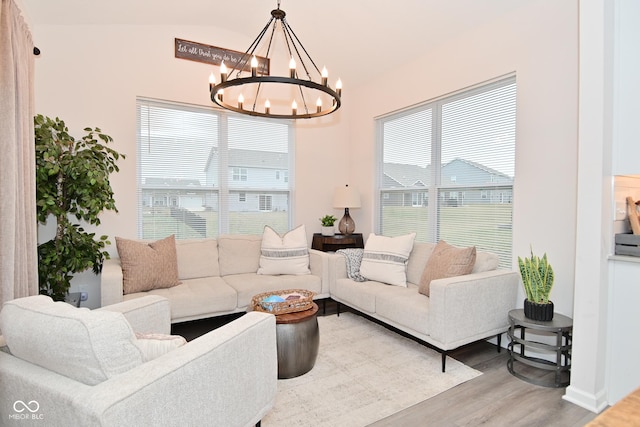 living area with a healthy amount of sunlight, an inviting chandelier, and wood finished floors