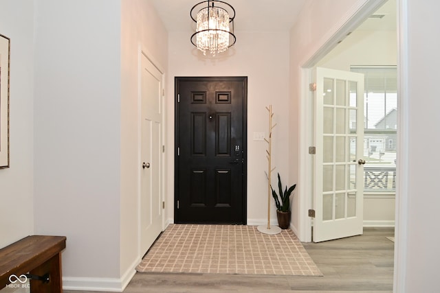 entryway featuring light wood-style flooring, visible vents, baseboards, and a notable chandelier