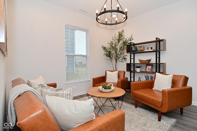 living area featuring baseboards, visible vents, a chandelier, and wood finished floors