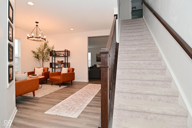 stairs with baseboards, an inviting chandelier, wood finished floors, and recessed lighting