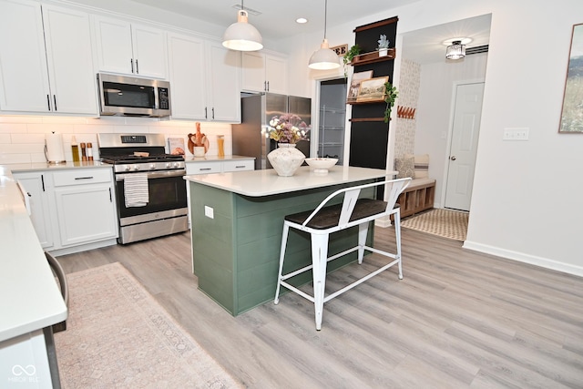 kitchen featuring a kitchen island, white cabinets, appliances with stainless steel finishes, backsplash, and light wood finished floors