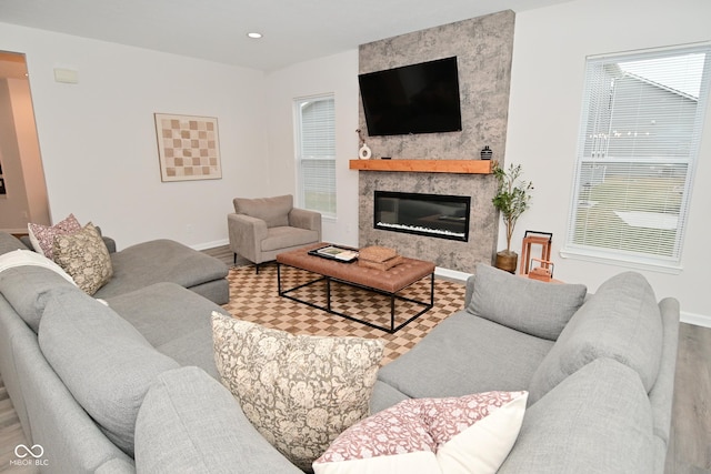 living area featuring a large fireplace, wood finished floors, and baseboards