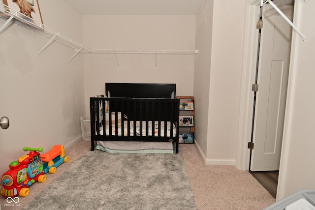 bedroom featuring a crib, baseboards, and carpet floors