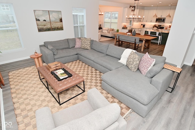 living room featuring baseboards, recessed lighting, wood finished floors, and an inviting chandelier