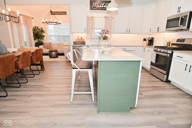 kitchen featuring tasteful backsplash, white cabinets, a center island, an inviting chandelier, and stainless steel appliances