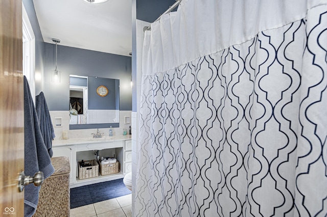 bathroom with toilet, a wainscoted wall, vanity, tile walls, and tile patterned floors