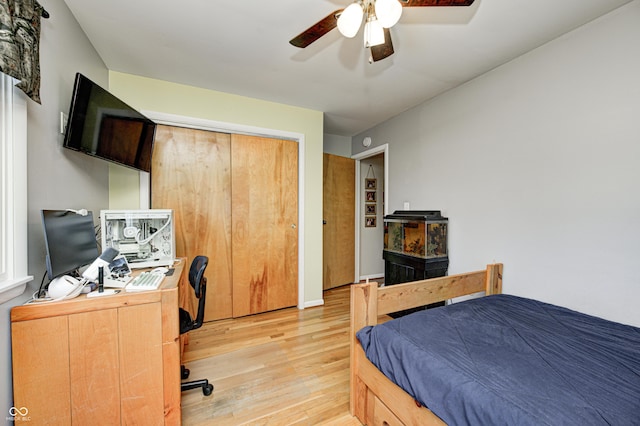 bedroom with ceiling fan, light wood finished floors, and a closet