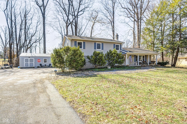 tri-level home with driveway, a chimney, an outbuilding, and a front yard