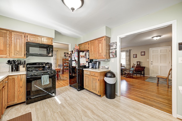 kitchen featuring light wood-type flooring, baseboards, light countertops, and black appliances