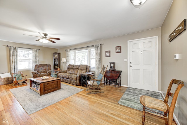 living area featuring hardwood / wood-style flooring, ceiling fan, and baseboards