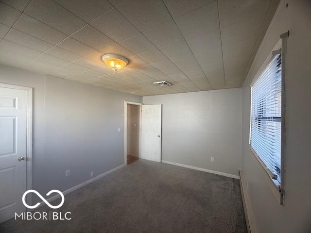 carpeted spare room with visible vents and baseboards