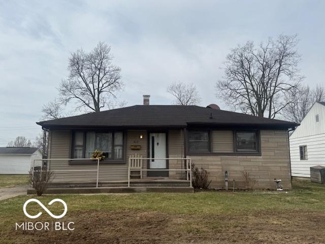 view of front of property featuring covered porch, a chimney, and a front lawn