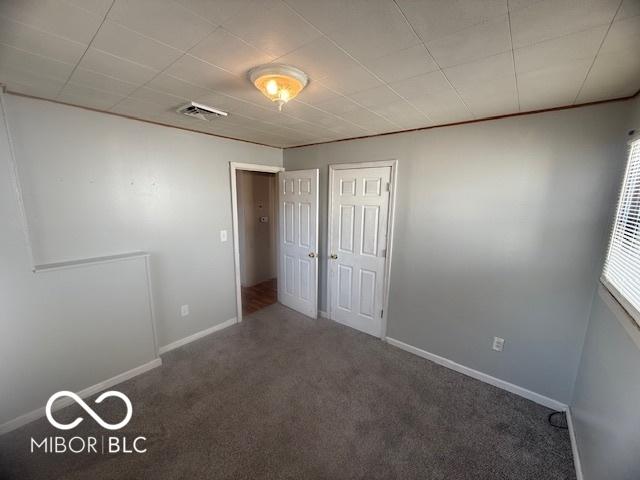 unfurnished bedroom with a closet, visible vents, baseboards, and carpet