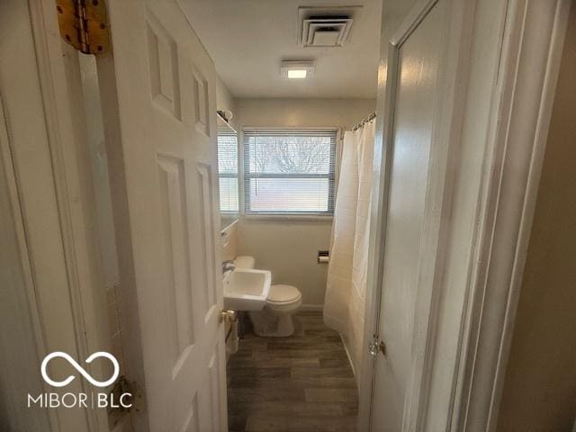 bathroom featuring visible vents, curtained shower, toilet, and wood finished floors