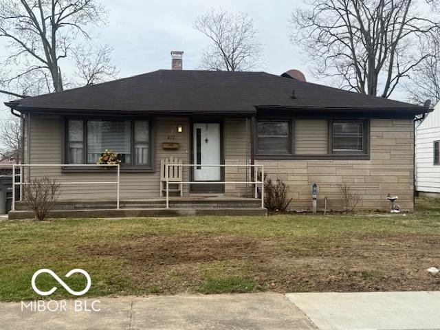 view of front of property featuring a front lawn, covered porch, stone siding, and a chimney