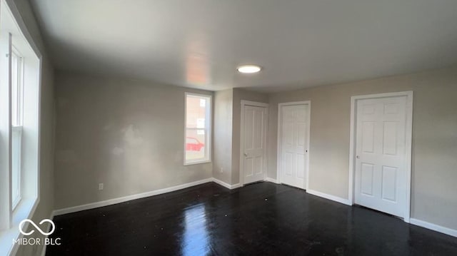 unfurnished bedroom featuring baseboards and dark wood-type flooring