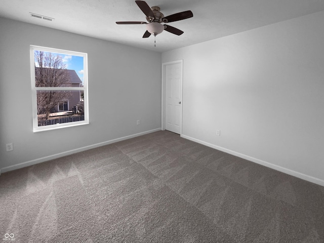 carpeted spare room featuring baseboards, visible vents, and a ceiling fan