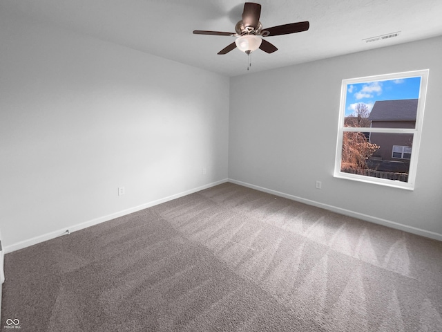 carpeted empty room featuring baseboards, visible vents, and a ceiling fan