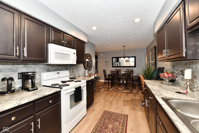 kitchen featuring dark brown cabinetry, white appliances, light countertops, and light wood finished floors