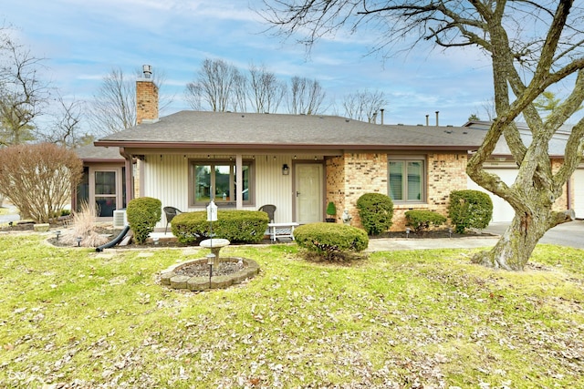 single story home with brick siding, a chimney, an attached garage, a front yard, and driveway