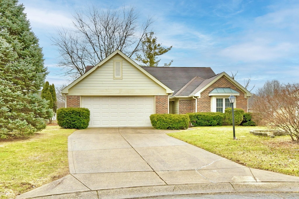 single story home featuring a garage, a front yard, brick siding, and driveway