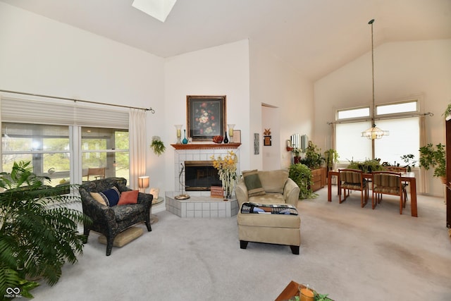 carpeted living room with a skylight, plenty of natural light, a fireplace, and high vaulted ceiling