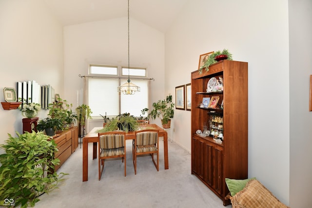 dining area featuring high vaulted ceiling and light colored carpet