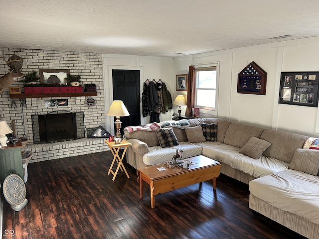 living area with a textured ceiling, a brick fireplace, wood finished floors, and visible vents