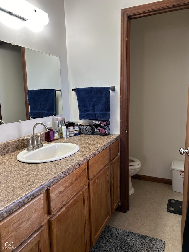 bathroom featuring toilet, baseboards, and vanity