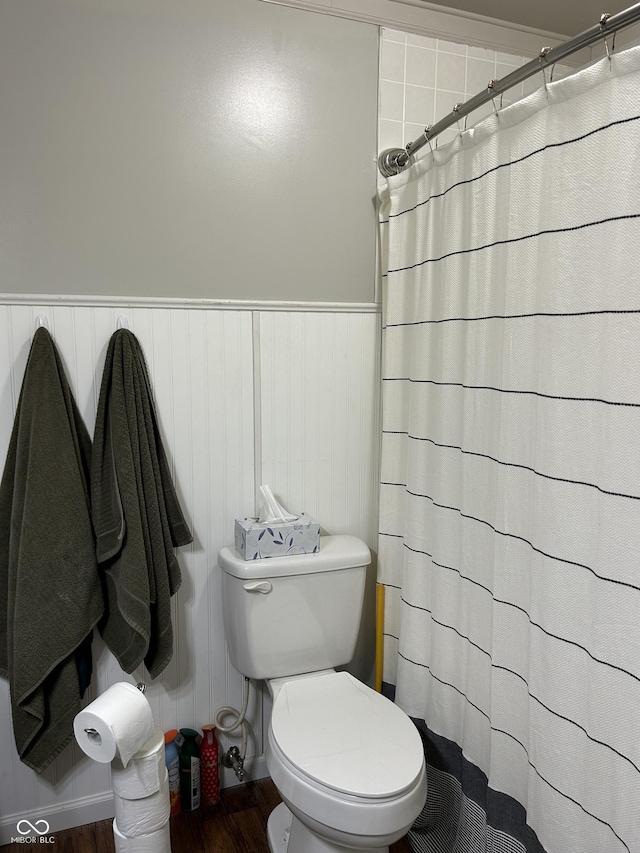 bathroom with a shower with shower curtain, wainscoting, toilet, and wood finished floors