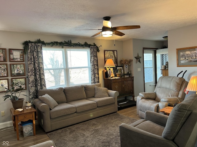 living area with a ceiling fan, a textured ceiling, baseboards, and wood finished floors