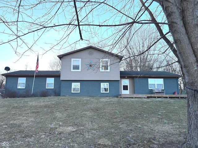 rear view of house with brick siding, a lawn, and a wooden deck