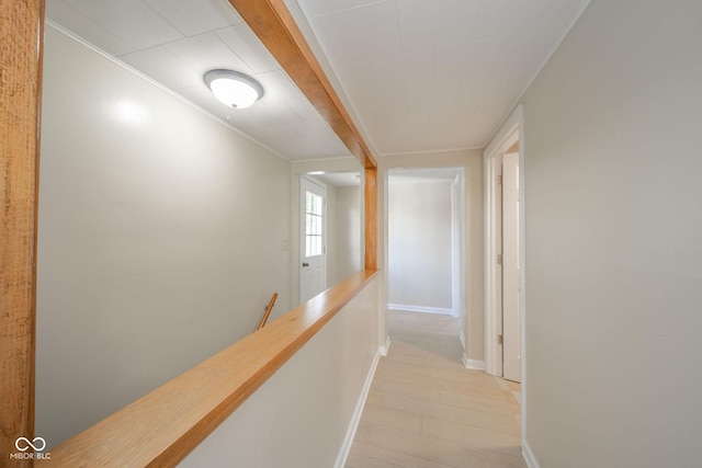 hall featuring light wood-type flooring, baseboards, and an upstairs landing