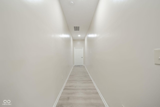 corridor featuring light wood-type flooring, visible vents, and baseboards