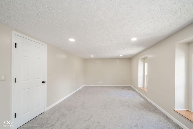 unfurnished room with a textured ceiling, recessed lighting, carpet, and baseboards