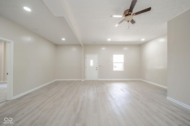 empty room featuring a textured ceiling, light wood finished floors, and baseboards