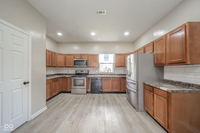 kitchen featuring stainless steel appliances, a sink, visible vents, and brown cabinets