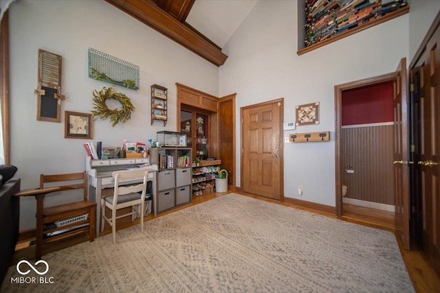 office space with high vaulted ceiling, baseboards, and wood finished floors