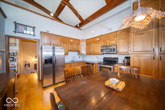 kitchen featuring light wood finished floors, brown cabinetry, dark countertops, stainless steel appliances, and a sink