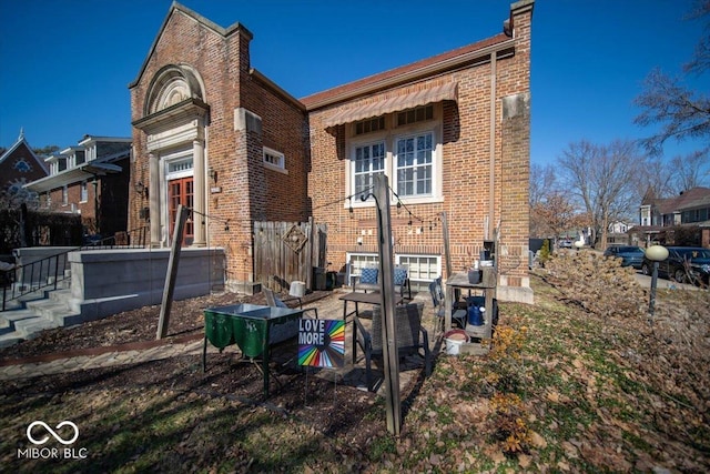 back of property with a chimney and brick siding