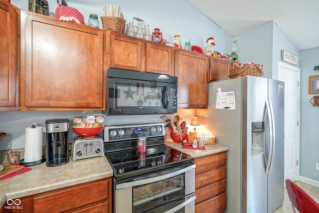 kitchen with brown cabinetry, appliances with stainless steel finishes, a textured ceiling, and light countertops