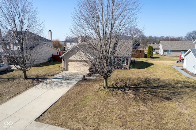 view of front of home featuring an attached garage, concrete driveway, and a front lawn