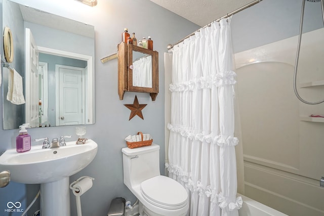 bathroom featuring a textured ceiling, toilet, shower / bath combo, and a sink