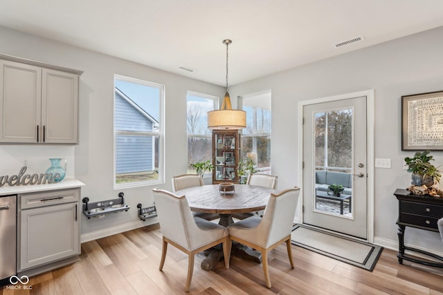 dining area with visible vents, light wood-style flooring, and baseboards