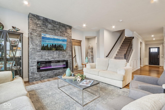 living area with wainscoting, stairway, wood finished floors, a fireplace, and recessed lighting