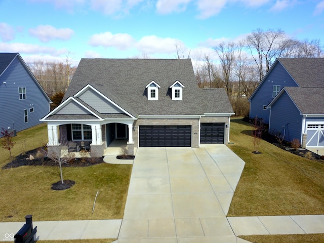 view of front facade with a garage, a shingled roof, concrete driveway, a porch, and a front yard