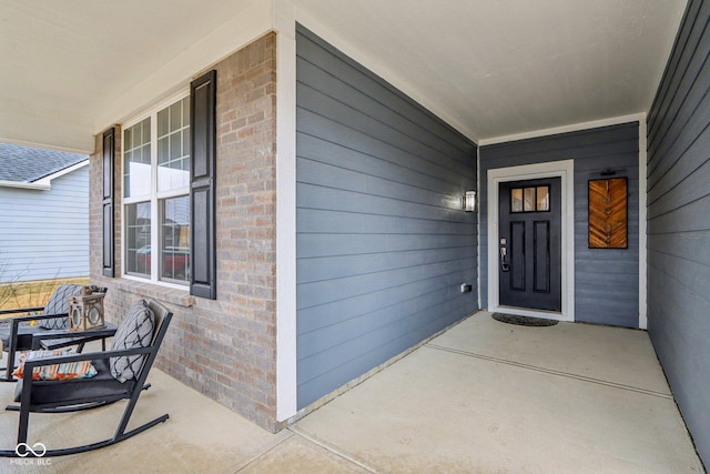 view of exterior entry with covered porch and brick siding