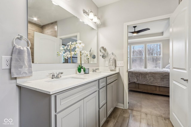 ensuite bathroom with double vanity, a sink, ensuite bath, and wood finished floors