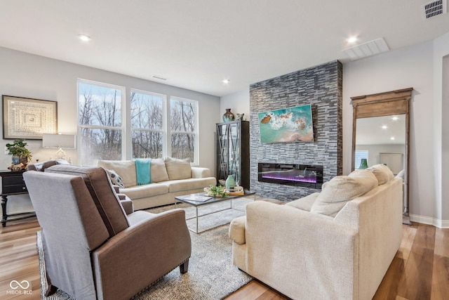 living area featuring light wood-type flooring, visible vents, and a fireplace