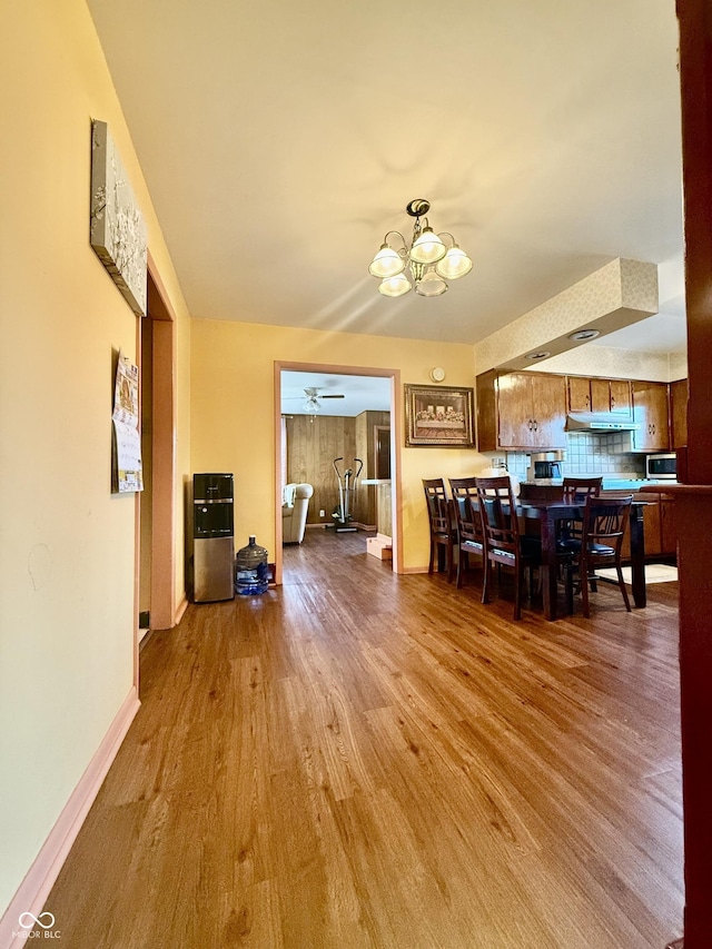 dining space with ceiling fan with notable chandelier, light wood-style flooring, and baseboards